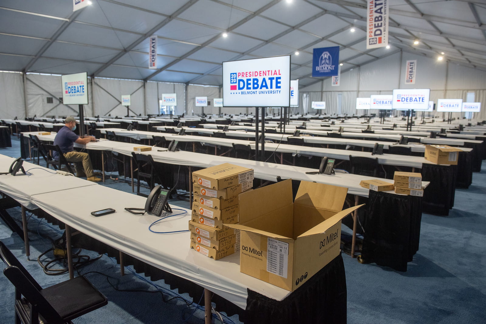 Rows of tables and monitors reading "2020 Presidential Debate: Belmont University" inside the media tent. Cardboard boxes sit on the corner of the closest table.