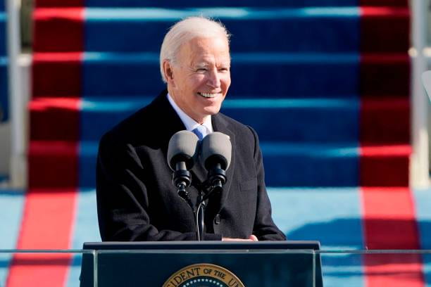 Joe Biden smiling in front of a podium at the US Capitol