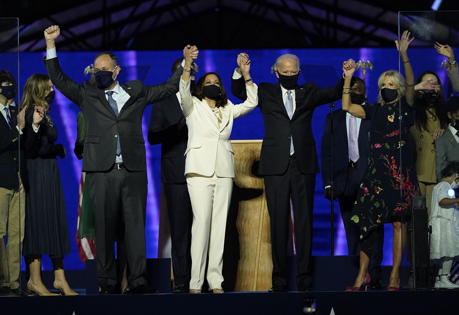 Kamala Harris, Joe Biden, and their spouses stand on stage holding hands